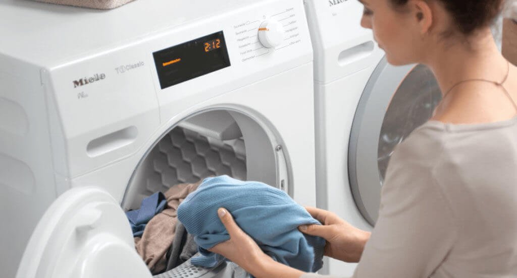 woman putting dirty laundry in her Miele washing machine