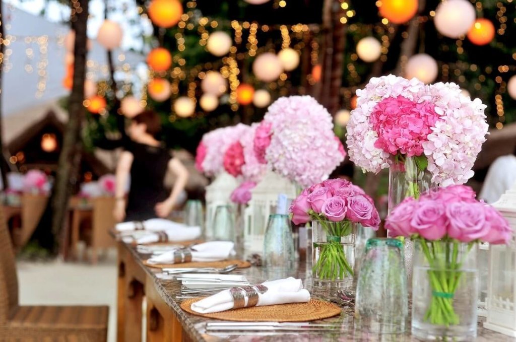 Pink hydrangeas and roses set on a dining table along with cutlery for a summer party