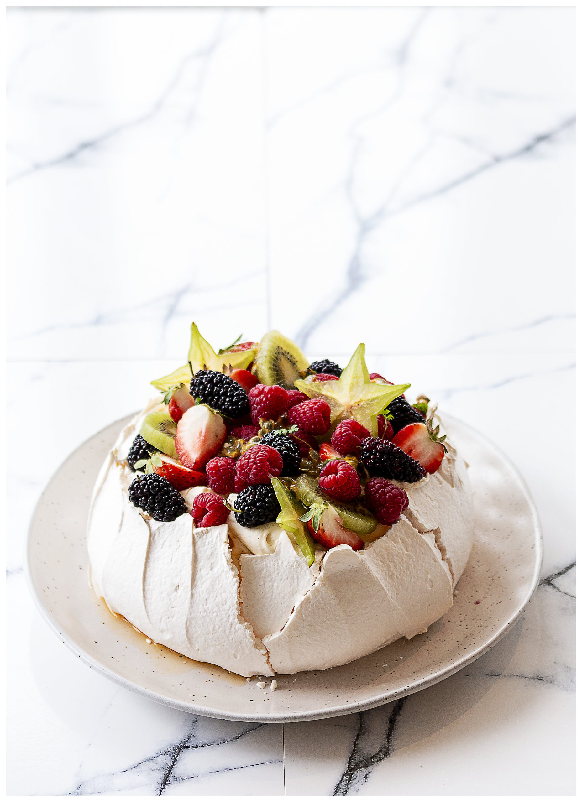 Traditional pavlova with strawberries, blackberries, raspberries, kiwis and starfruits christmas