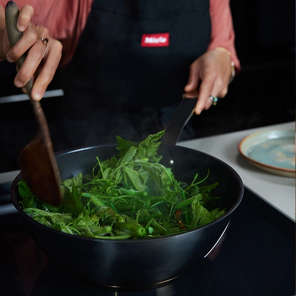 Palisa stir-frying vegetables in a Miele wok on a Miele induction cooktop